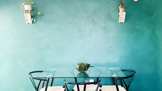 A dining area with a glass table and chairs, a vase with flowers, and two wall-mounted planters. - CoralXscape: curated 2 bedroom in Philly near everything! (Philadelphia)