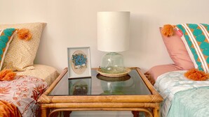 A small, wooden-framed table with a glass top, a white lamp, and a framed picture on it. - CoralXscape: curated 2 bedroom in Philly near everything! (Philadelphia)