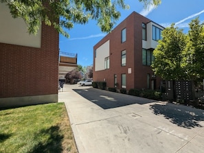 A residential street with modern brick buildings, a clear sky, and a sidewalk.