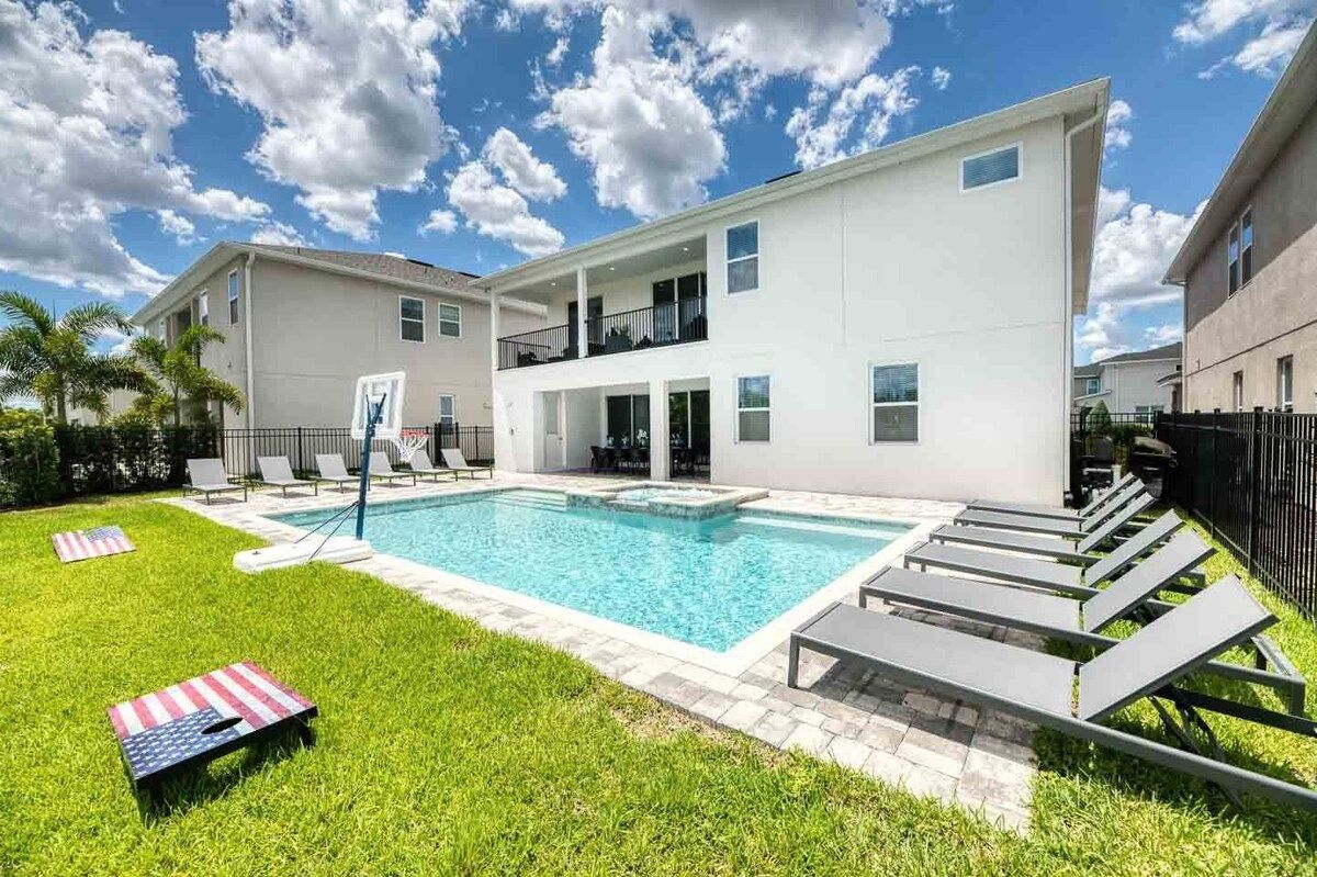 A two-story building with a swimming pool, outdoor seating, and a well-maintained lawn.