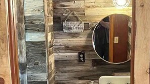A bathroom with a wooden wall design, a wooden vanity with a mirror, a sink, and a basket.