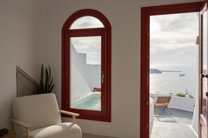 A room with a view of a swimming pool and the sea.
