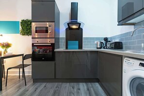 A compact kitchen with a built-in oven, microwave, and a modern espresso machine. - Modern City Centre Apt Near Theatre & Marina (Kingston upon Hull)