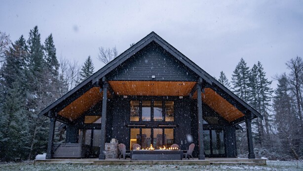 Una baita con camino, veranda in legno e portico coperto.