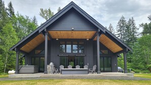 Una casa moderna con un ampio portico, un barbecue e un'area salotto.