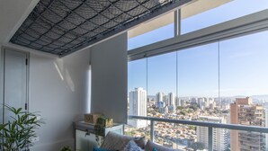 Un salon moderne avec une grande fenêtre, un canapé, une petite table et une plante en pot.