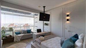 Une chambre moderne avec un grand lit, un bureau et un téléviseur fixé au mur.