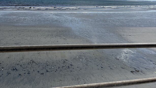 Une plage avec un ciel dégagé et des vagues.