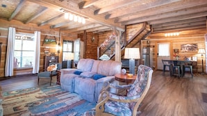 A log cabin interior with a sofa, armchairs, a dining table, and a staircase. - Updated pet friendly, close to Nashville! (Nashville)