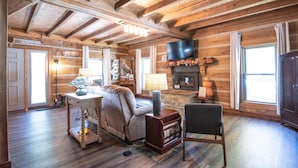 A cozy log cabin interior with a fireplace, a television, and a comfortable seating area. - Updated pet friendly, close to Nashville! (Nashville)