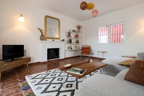 A living room with a television, fireplace, sofa, coffee table, and decorative items.