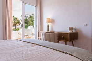 A hotel room with a bed, a desk with a lamp, and a view of the outdoors.