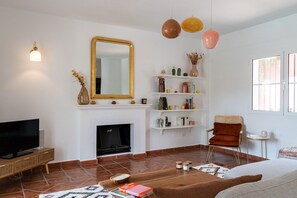 Una sala de estar con chimenea, televisor y una estantería.