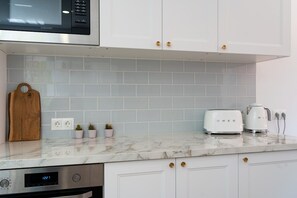 Una cocina con armarios blancos, microondas, tostadora y cafetera.