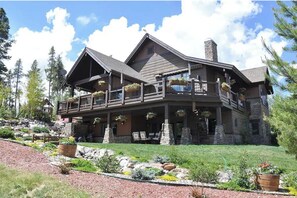 Set amidst a lush garden, this lodge features a charming balcony and a stone chimney.