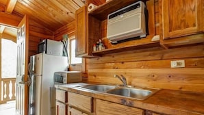 Interno di una baita in legno con angolo cottura, dotato di frigorifero, microonde, tostapane e forno a incasso.