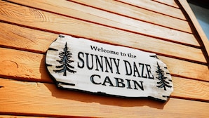 Segno di legno con la scritta 'Welcome to the SUNNY DAZE CABIN'.