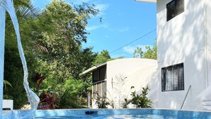 En pool med krystalklart blå vand, omgivet af frodig vegetation og moderne arkitektur.