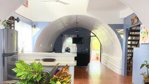 Et køkken med buet loft, et køleskab, en vask og et spiseområde med et bord og stole.