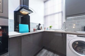 Eine moderne Küche mit eingebautem Geschirrspüler, Herd und Fenster mit Jalousien.