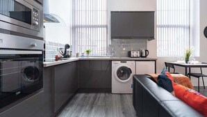 A compact kitchen with a washing machine, a microwave, and a toaster.