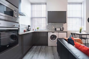 A compact kitchen with a washing machine, a microwave, and a toaster. - Central Condo Hull Apartment w/ Smart TV (Kingston upon Hull)