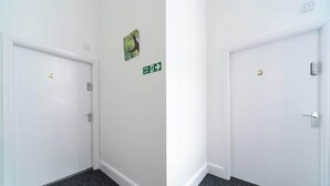 A hallway with two white doors, one marked with the number 4 and the other with the number 3. There is a green emergency exit sign on the wall.