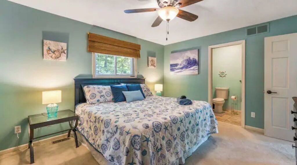 Ein Schlafzimmer mit Bett, Deckenventilator, Fenster, Nachttisch und einer Tür.