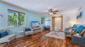 Relax in this inviting living room with a sofa, armchairs, and large windows.