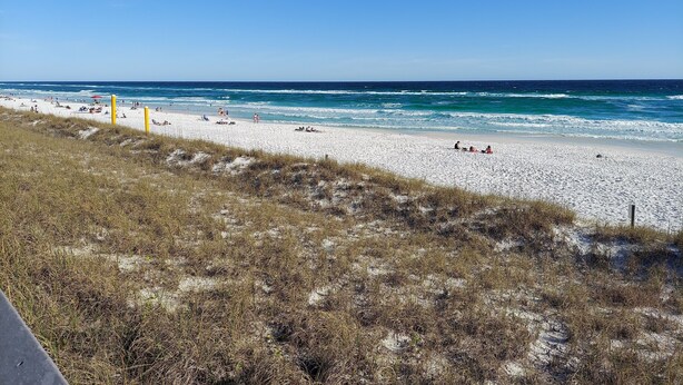 A beach with white sand and ocean waves.