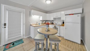 A modern kitchen with white cabinets, a central island, and a refrigerator.