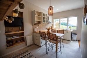 Una cocina moderna con comedor, armarios empotrados, un ventanal grande y un televisor.