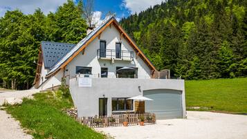 Un chalet à deux étages, doté d’un toit en pente, d’un balcon et d’un garage.