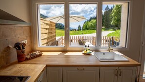 Eine Küche mit einem großen Fenster, einer Holz Arbeitsplatte und einem Spülbecken.