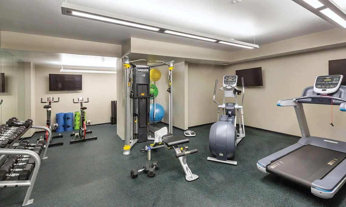 A gym with cardio machines, free weights, and a weight bench.