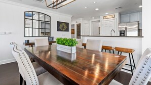A modern dining room with a wooden table, white chairs, and a decorative plant centerpiece.