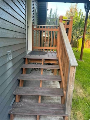 Un escalier en bois menant à un porche doté d’une rampe en métal.