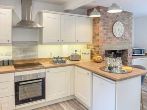 A modern kitchen with white cabinetry, a brick accent wall, a built-in oven, and a microwave. - 3 bedroom accommodation in Mills Croft, near Hognaston (Mills Croft, near Hognaston)