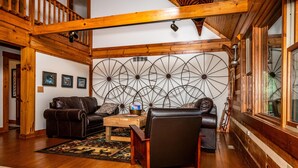 Ein geräumiges Wohnzimmer mit Holzboden, einer großen Wanddekoration mit Windmühle, Ledersofas und einem Holztisch.