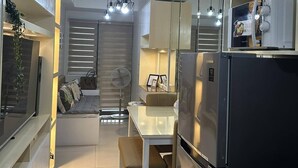 A modern kitchen with a refrigerator, dining table, and hanging pendant lights. - Mel and Rose Place at S Residences Tower 1 Mall of Asia Area (Pasay)