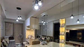 A modern living room with a glass dining table, brown leather chairs, and pendant lighting. - Mel and Rose Place at S Residences Tower 1 Mall of Asia Area (Pasay)