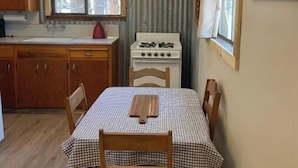 Eine kleine Küche mit Herd, Holzschränken und einem Fenster.