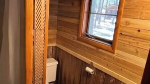 Ein Badezimmer einer Holzhütte mit Toilette und Waschbecken.