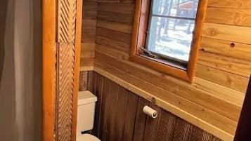 A wooden cabin bathroom with a toilet and a sink.