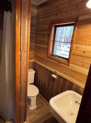 Un baño de cabaña de madera con inodoro y lavabo.
