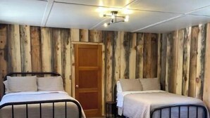 Ein Zimmer mit zwei Betten, Holzwänden, einer Deckenleuchte und einem Holzboden.