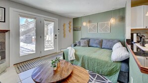 Ein gemütliches Zimmer mit einem Bett, einem runden Holztisch und Blick ins Freie.