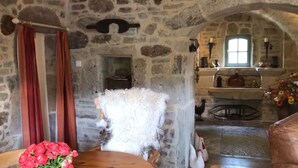 A stone-walled room with a rustic fireplace, a wooden table with a vase of flowers, and a cozy seating area. - La Salesse, Restored farmhouse in idyllic rural location + private pool (Ginals)