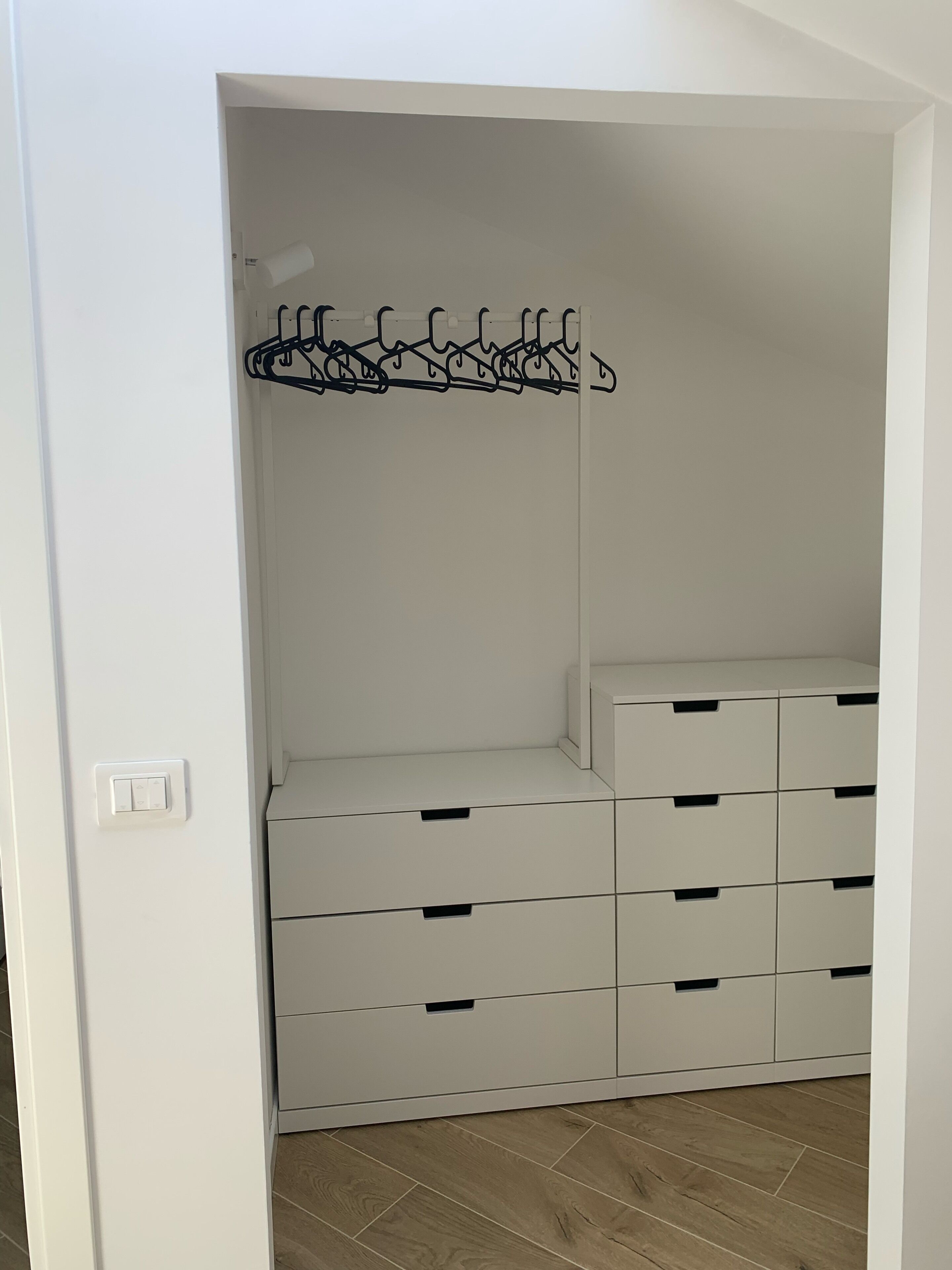 Een witte kast met meerdere lades en een kledingroede.