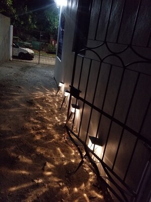 A gated entrance with a metal fence and two wall-mounted lights. - Newly built, quiet neighborhood,  fruited, and affordable (Kingston)